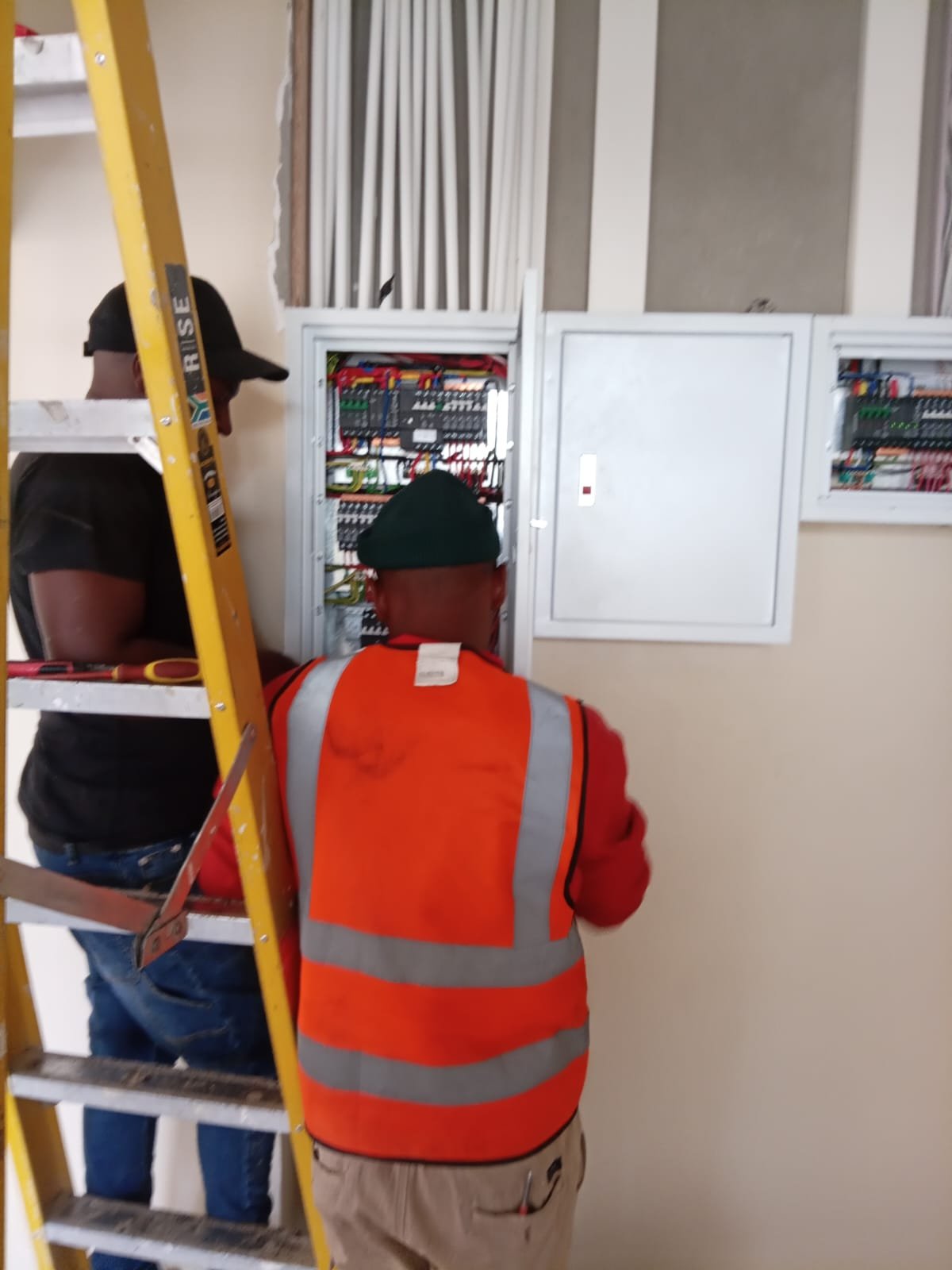 Power Plumbers & Electrical technicians wiring a commercial distribution board